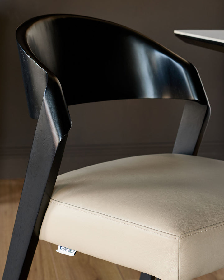 Enzo dining chair with black curved backrest and natural leather seat, side angle view