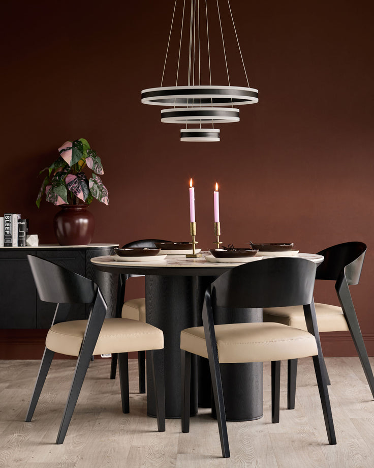 Enzo dining chair in black wood with natural leather seat, shown at round dining table in burgundy room setting.