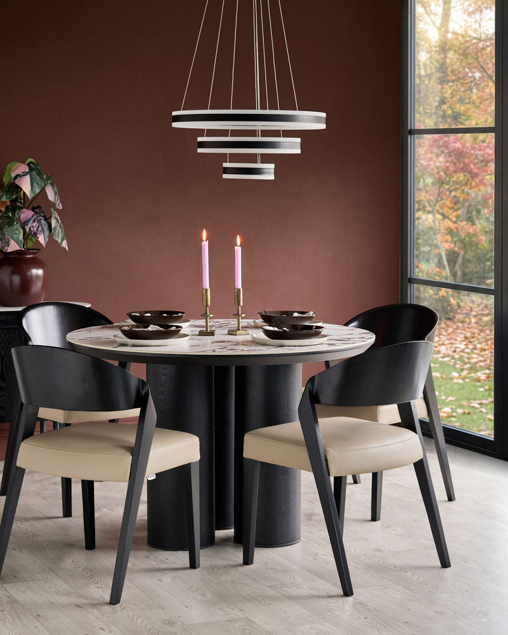 Enzo dining chair in black wood with natural leather seat, shown at round marble table in modern dining room setting.