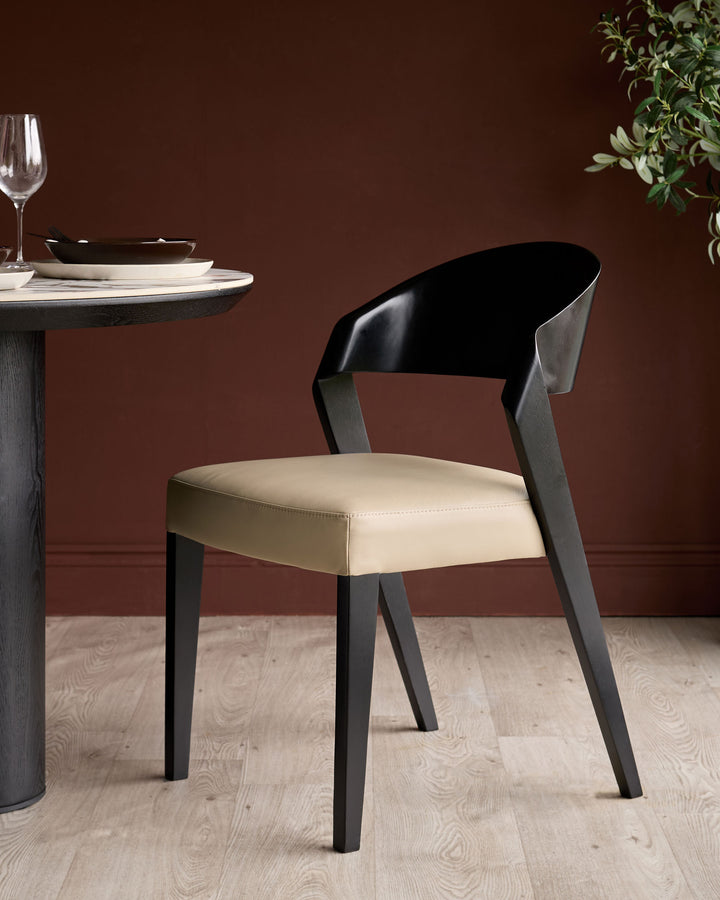 Enzo dining chair in natural leather with black curved backrest and dark wooden legs, shown at round table setting.