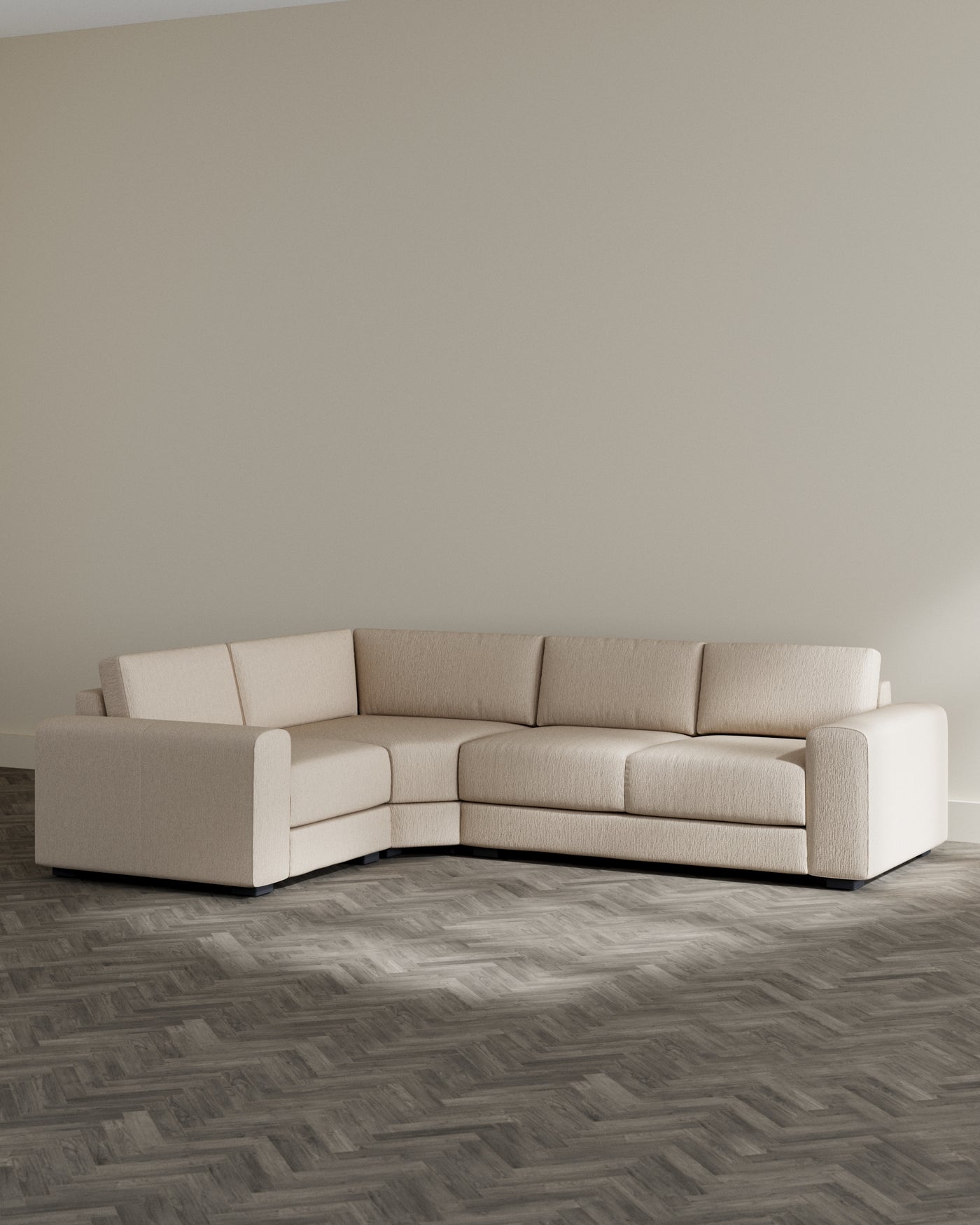 Beige contemporary L-shaped sectional sofa with a clean design and plush cushions, set on a grey herringbone-patterned floor.