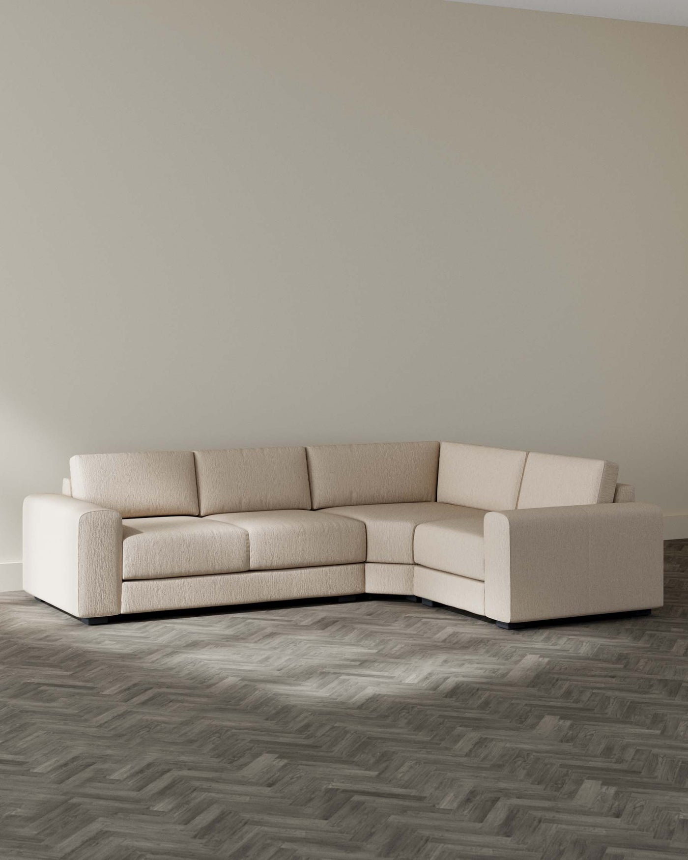 Modern beige corner sectional sofa with minimalist design and textured upholstery, featuring a clean-lined silhouette with a low backrest and wide, plush seating, set on a herringbone patterned wooden floor.