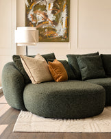 Eris left-hand corner chaise sofa in dark green fabric, styled with patterned pillows and a cream rug in a bright interior.