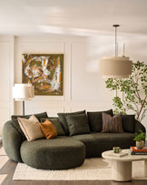 Dark green fabric left-hand corner chaise sofa with curved armrests, styled in a bright living room with neutral décor.