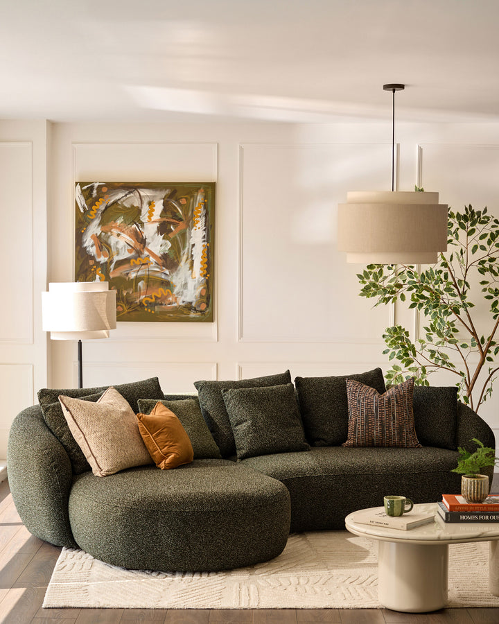 Dark green fabric left-hand corner chaise sofa with curved armrests, styled in a bright living room with neutral décor.