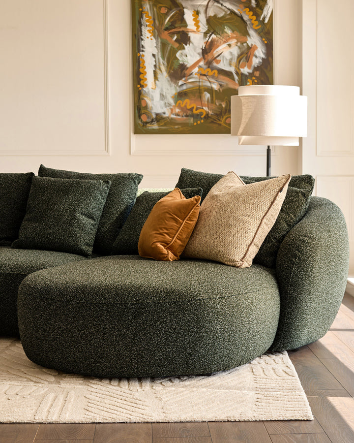 Eris right-hand corner chaise sofa in dark green fabric with decorative pillows in a styled living room setting.