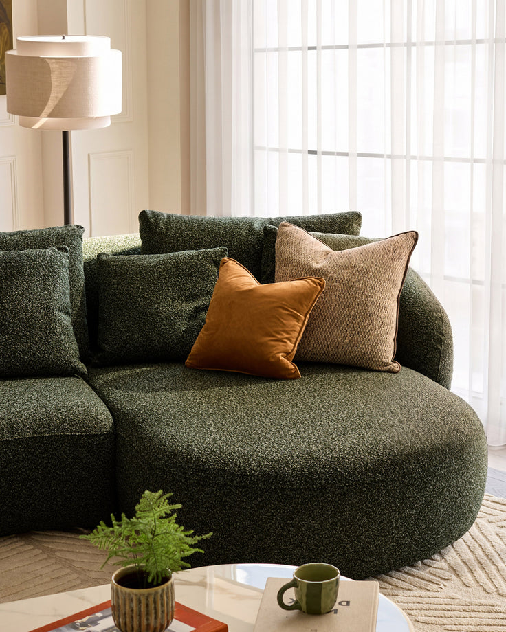 Dark green Eris right-hand corner chaise sofa with decorative pillows in a bright living room setting.
