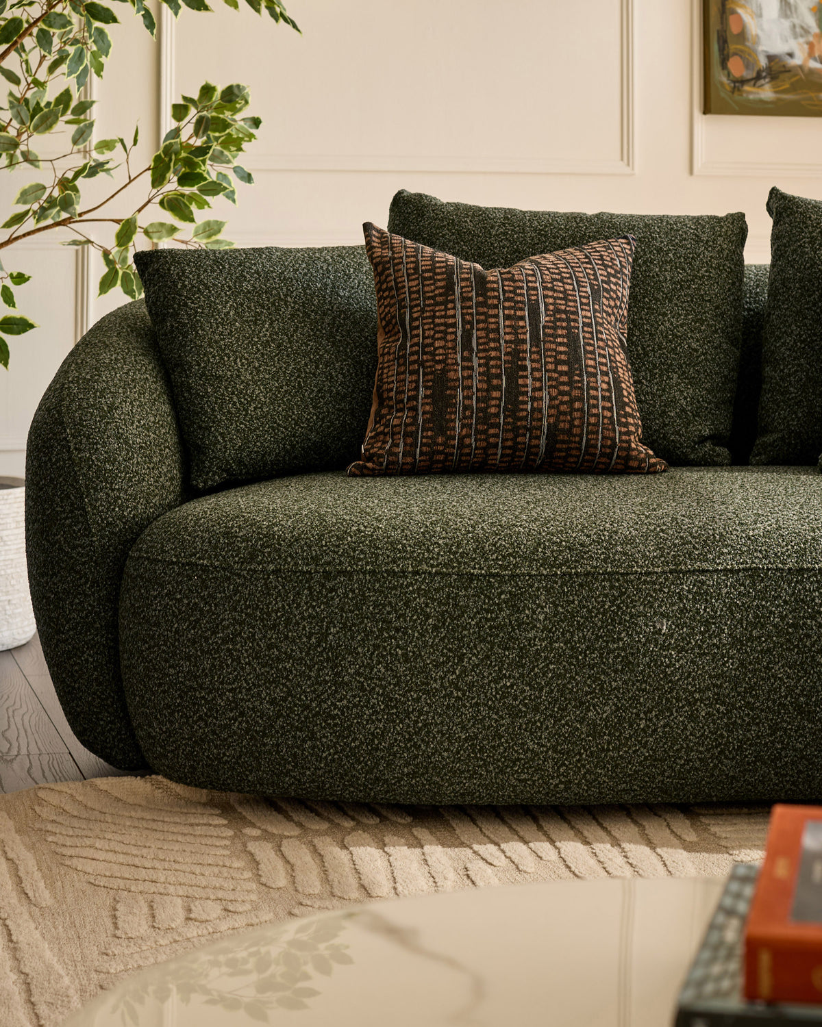 Dark green upholstered right-hand corner chaise sofa with curved arms, styled with patterned brown cushion and potted plant.