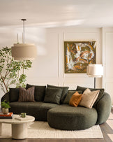 Dark green fabric right-hand corner chaise sofa with curved, rounded arms and plush cushions in a modern living room setting.