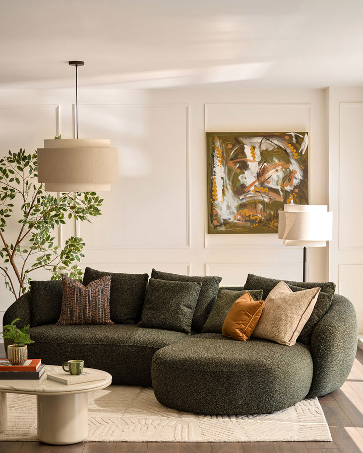Dark green fabric right-hand corner chaise sofa with curved, rounded arms and plush cushions in a modern living room setting.