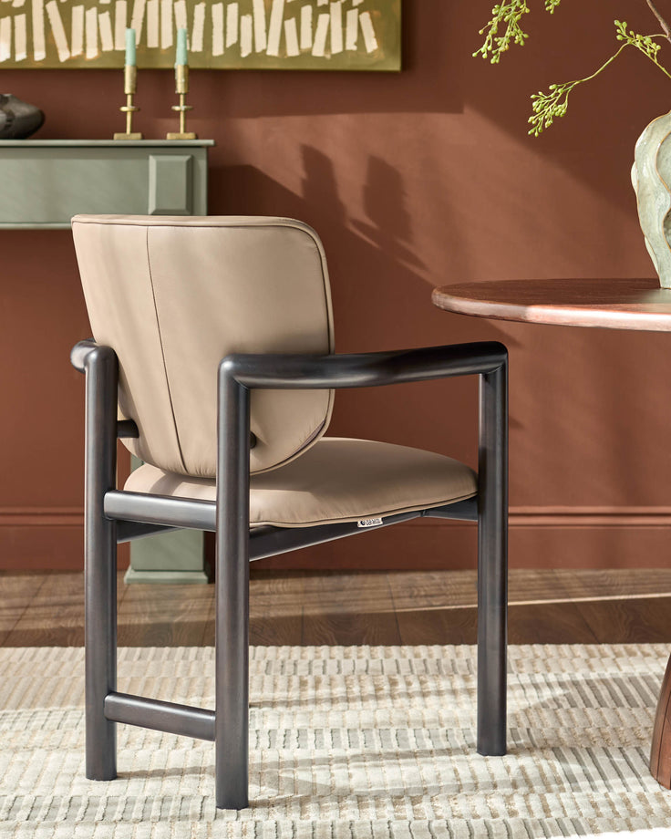 Esme dining chair in mocha leather with dark metal frame, shown in a styled room setting with terracotta walls.
