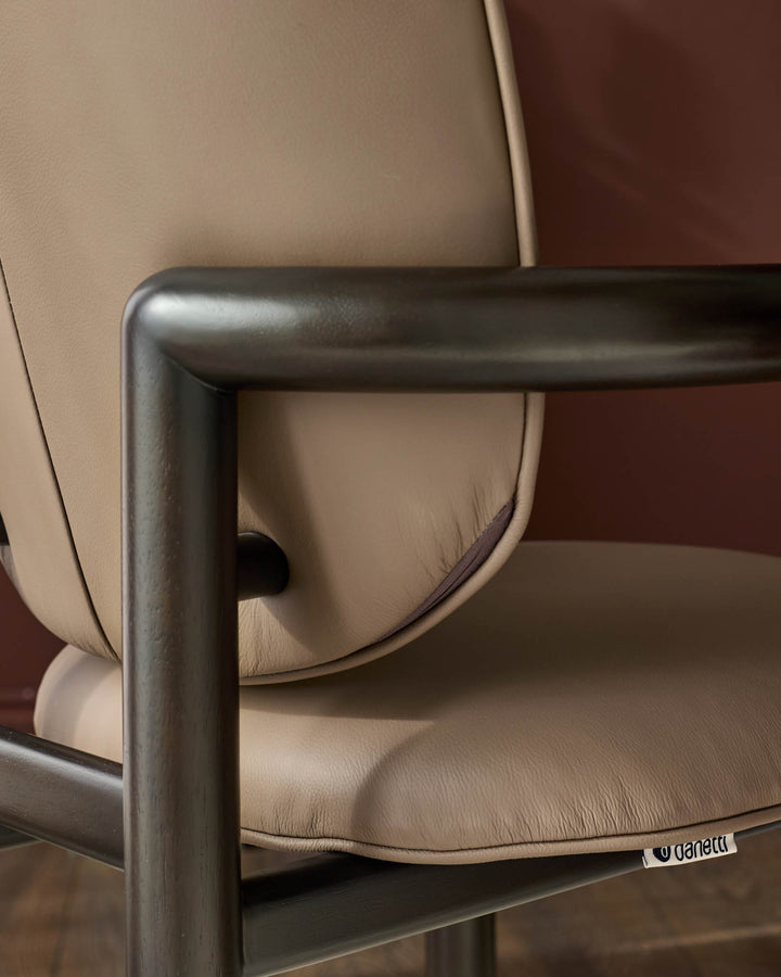 Esme dining chair in mocha leather, showing curved backrest and metal frame detail from side angle.