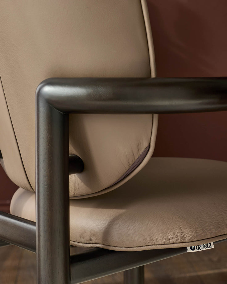 Esme dining chair in mocha leather, showing curved backrest and metal frame detail from side angle.