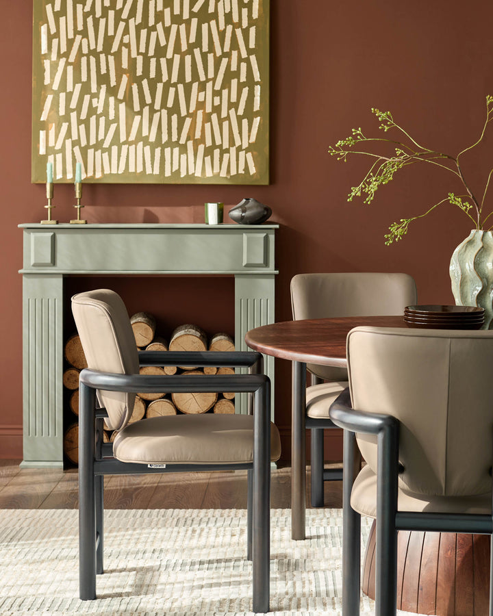 Esme dining chair in mocha leather with black metal frame, shown in a styled dining room setting.