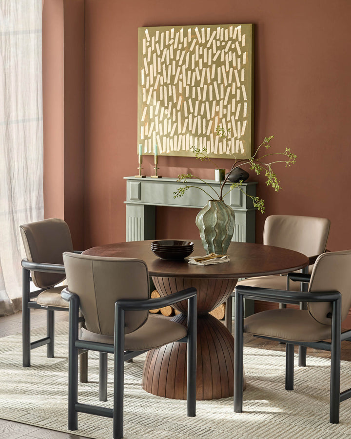 Esme dining chair in mocha leather with black metal frame, shown around round wood table in warm dining room setting.