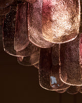 Smoked glass chandelier with ombre finish, close-up detail showing textured surface and curved glass panels with warm lighting.