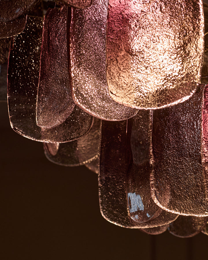 Smoked glass chandelier with ombre finish, close-up detail showing textured surface and curved glass panels with warm lighting.
