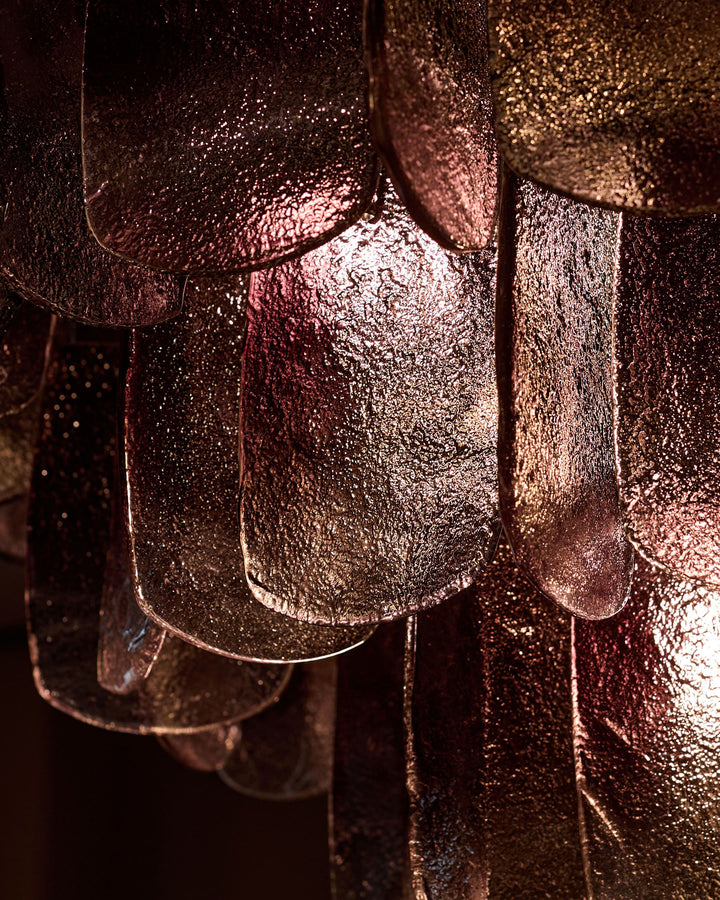 Estelle chandelier close-up showing smoked glass with golden-bronze ombre finish and textured surface detail.