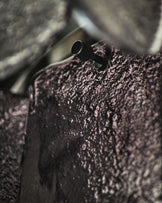 Smoked glass chandelier with textured ombre finish and black metal fixture detail, close-up view.