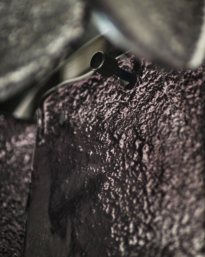 Smoked glass chandelier with textured ombre finish and black metal fixture detail, close-up view.
