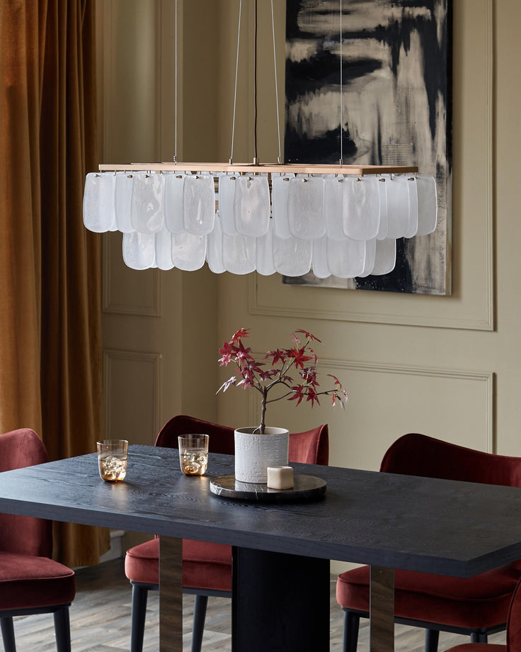 A dining room featuring a dark wood table, plush velvet chairs, statement chandelier and decorative pieces.