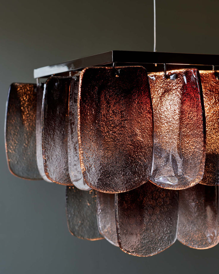 Modern light fixture with metallic frame and textured glass panels, creating a warm and ambient glow.