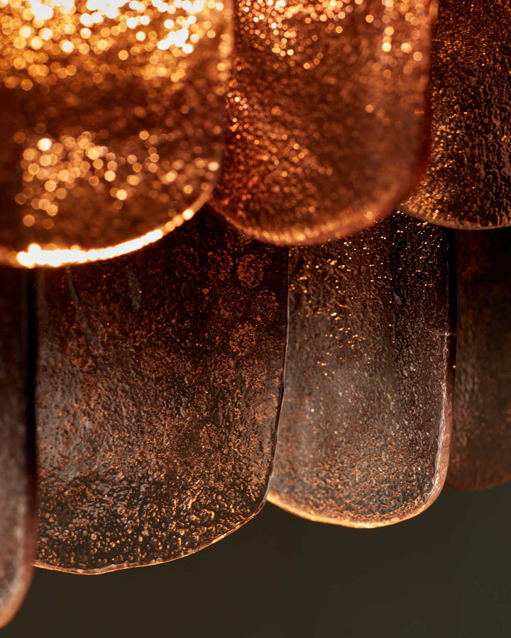 A close-up of a textured, petal-like light fixture with a warm, copper-toned finish. A modern and eye-catching design piece.