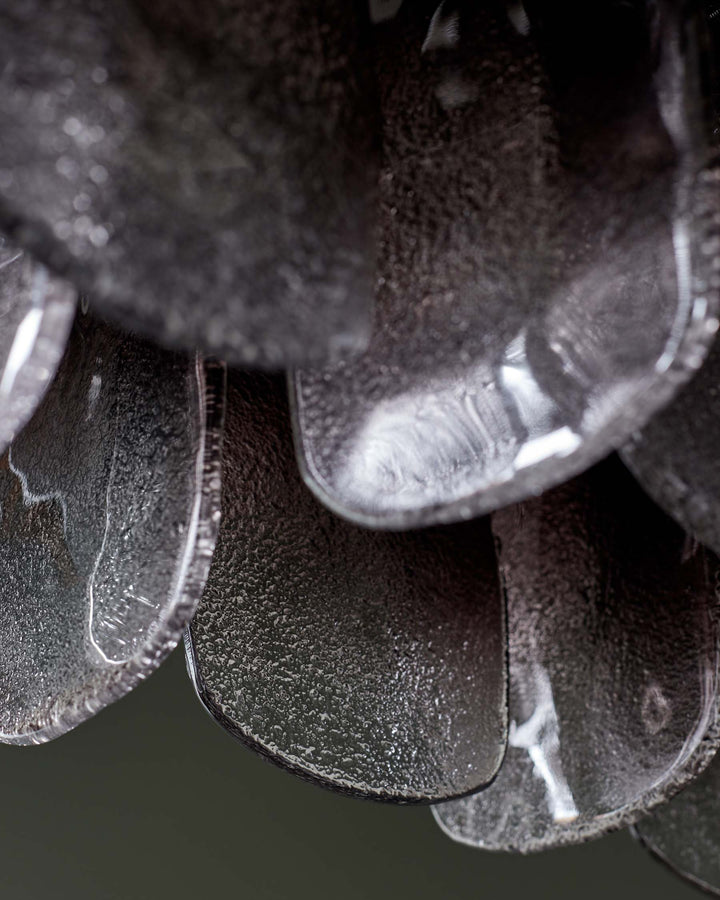 Close-up of a contemporary chandelier, featuring textured, translucent discs in layered, cascading arrangement.