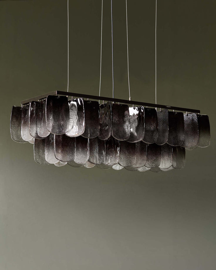 A rectangular chandelier with textural glass elements, suspended by slim cables, adds a touch of modern elegance.