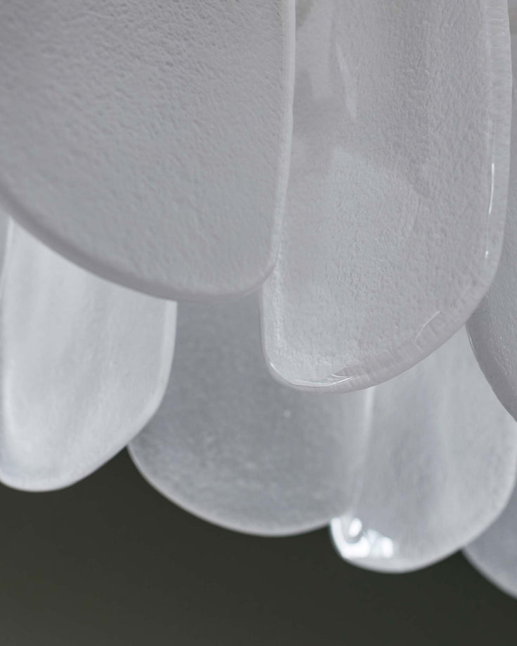 Close-up of layered, textured white glass light fixture, creating a soft, ethereal aesthetic.
