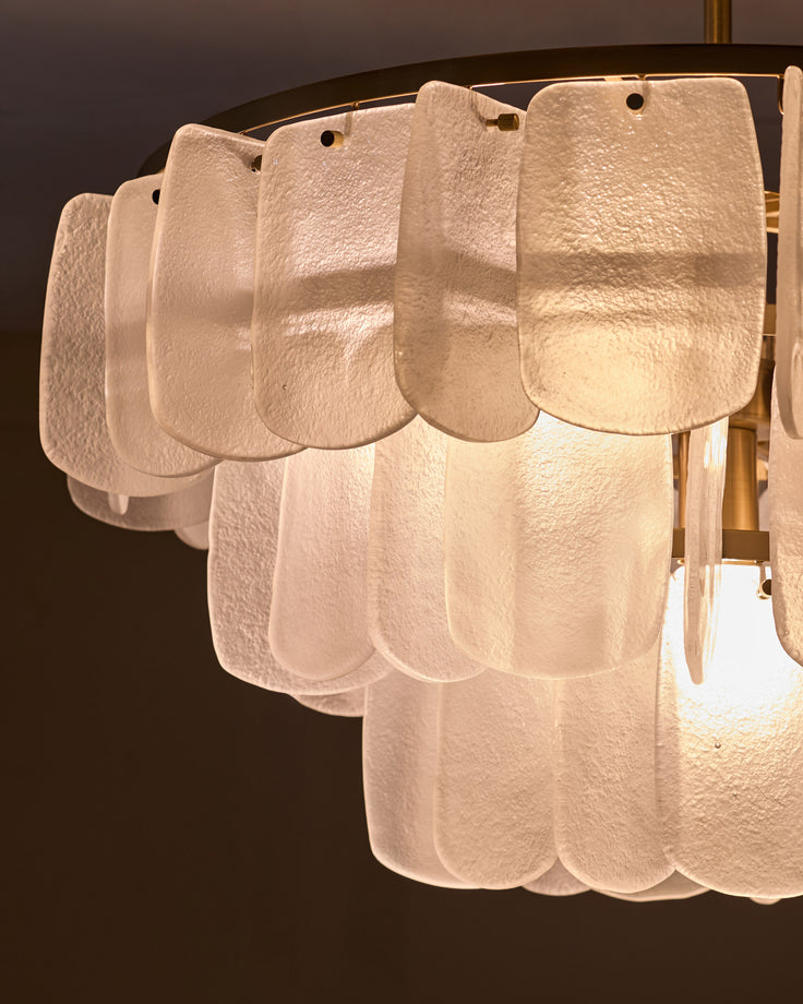 White frosted glass scalloped disc panels arranged in tiered rows on brass fixture, side angle view.
