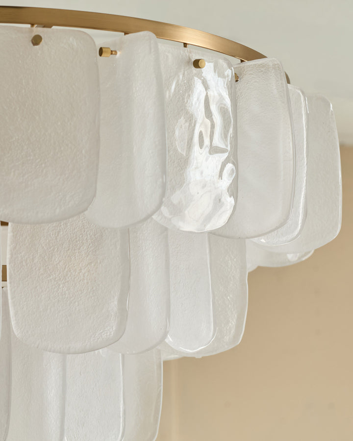 Estelle chandelier with white textured glass panels hanging from brass rod, detail view showing layered scalloped shades.