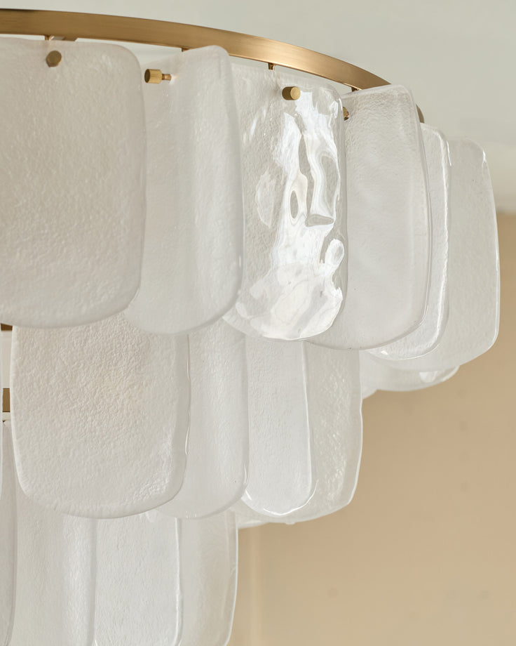 Estelle chandelier with white textured glass panels hanging from brass rod, detail view showing layered scalloped shades.
