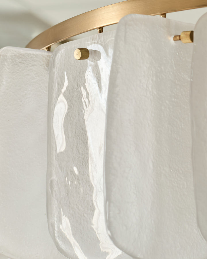 White textured glass panels hanging from brushed brass rod with brass knob fixtures on white wall.