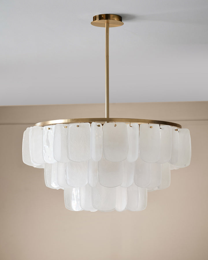 Estelle chandelier with brass finish frame and tiered white glass panels, suspended from ceiling.