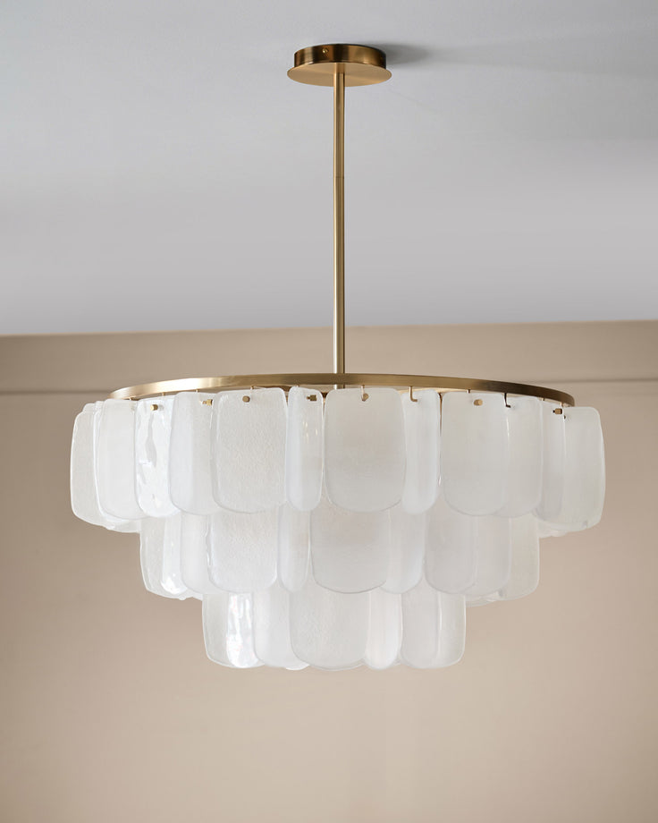 Estelle chandelier with brass finish frame and tiered white glass panels, suspended from ceiling.