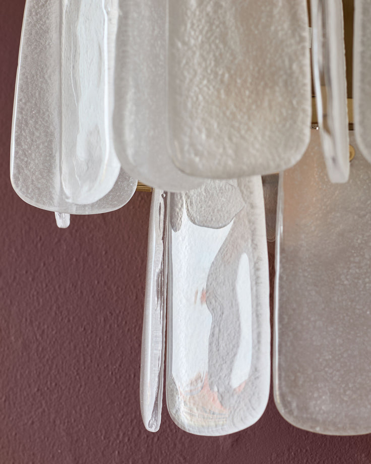 White glass wall light with curved shade and metal bracket, displayed against burgundy background.