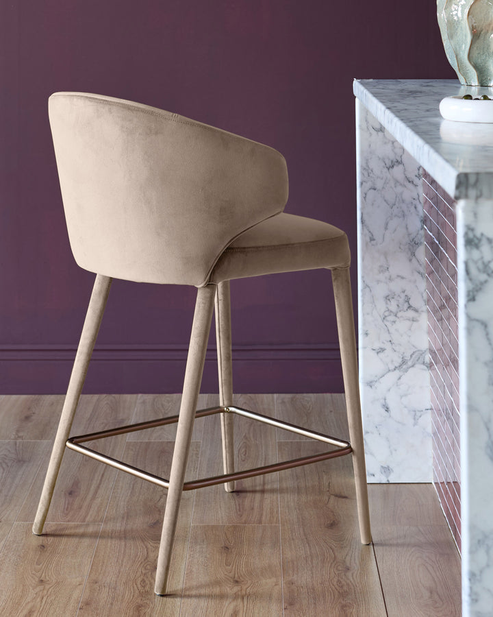 Ethan bar stool in champagne velvet, side view, showing curved backrest and wooden legs with footrest.