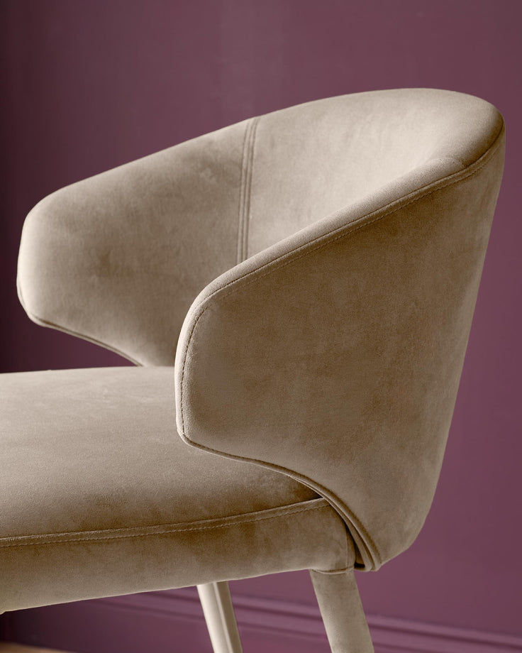 Ethan bar stool in champagne velvet, shown from side angle against purple background, featuring curved backrest and legs.