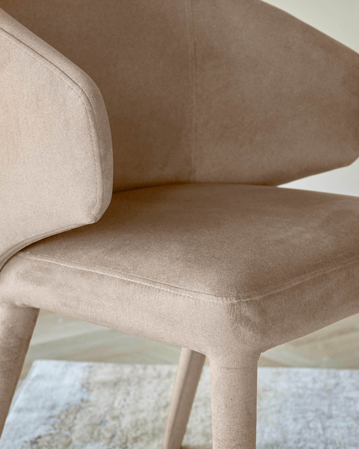 Ethan dining chair in champagne velvet, showing curved backrest and seat detail from a side angle.