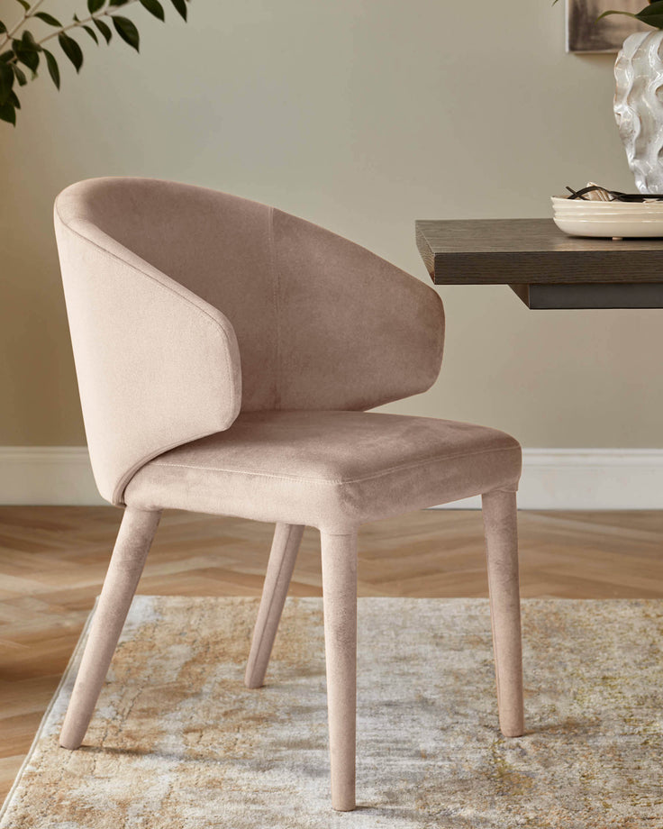 Ethan dining chair in champagne velvet with curved backrest and light wood legs, positioned at a desk.