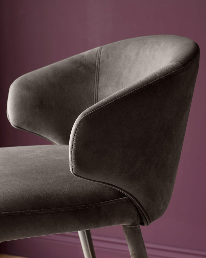 Ethan bar stool in dark chocolate velvet, shown from rear angle against purple background, displaying curved backrest and metal legs.