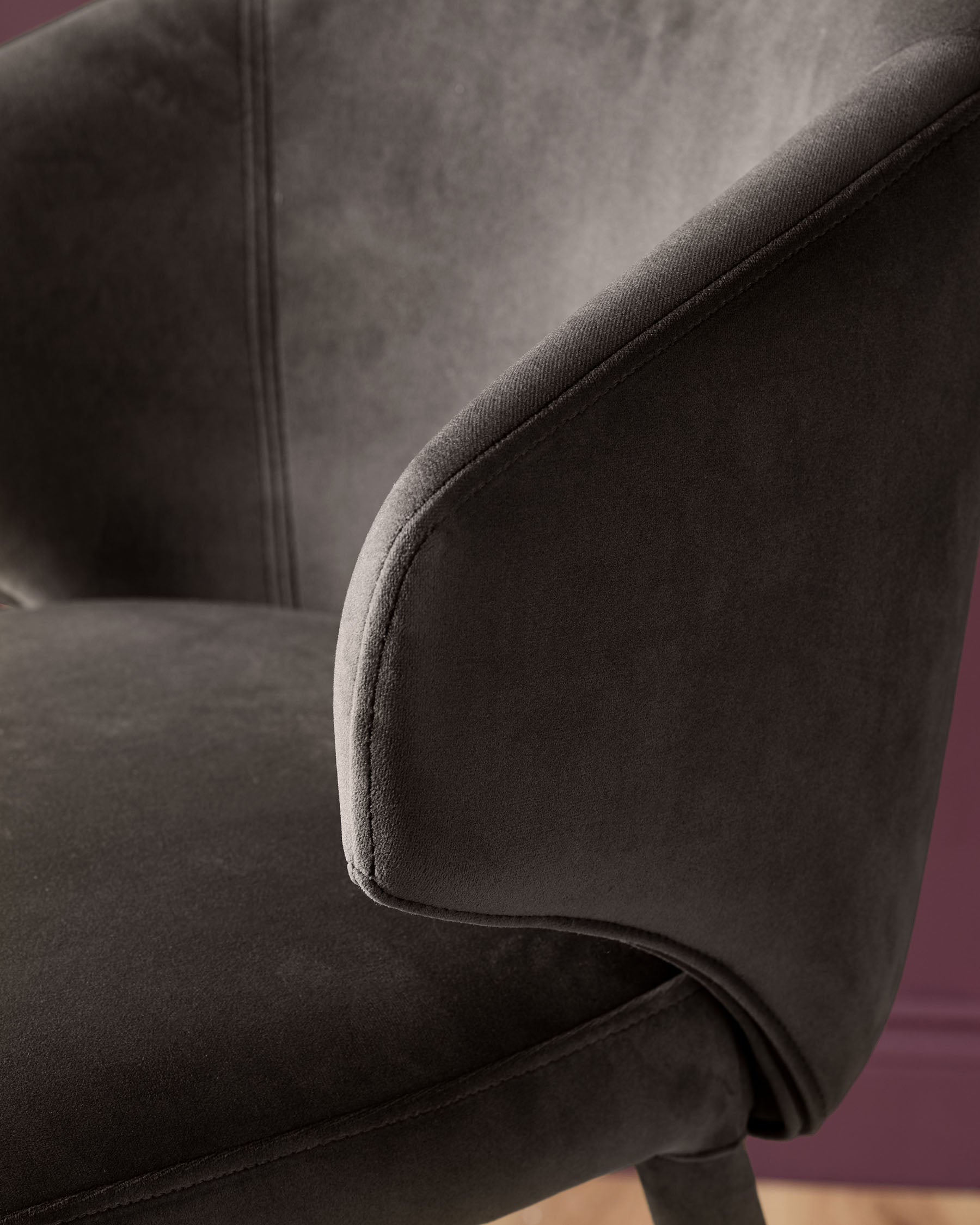 Dark chocolate velvet bar stool with curved backrest and piping detail, side view angle.