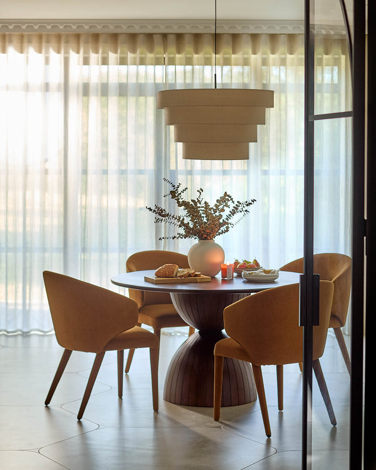 Malin 4-seater dining table in dark mango wood, round top with pedestal base, styled in modern dining room.