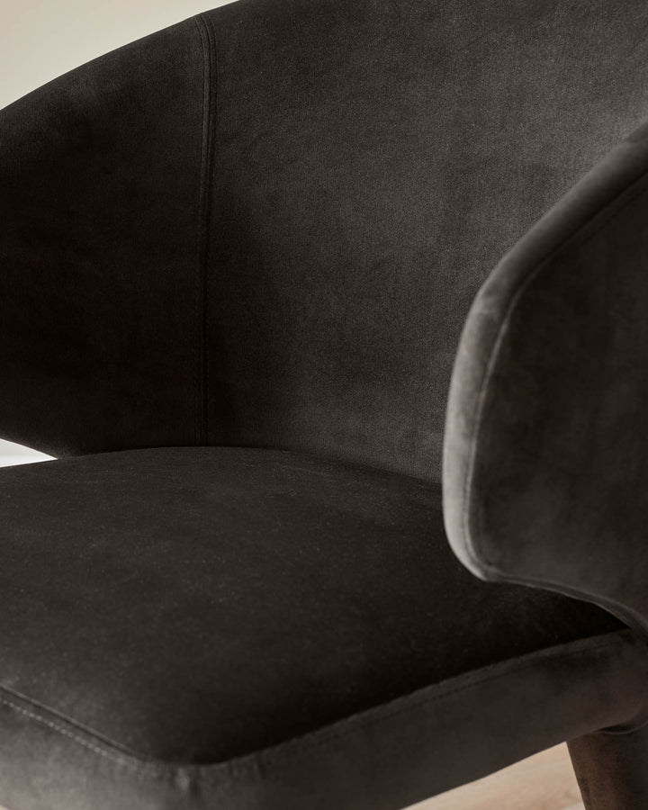 Close-up of a stylish, brown velvet chair showing the seat and armrest. Modern design for comfortable living.