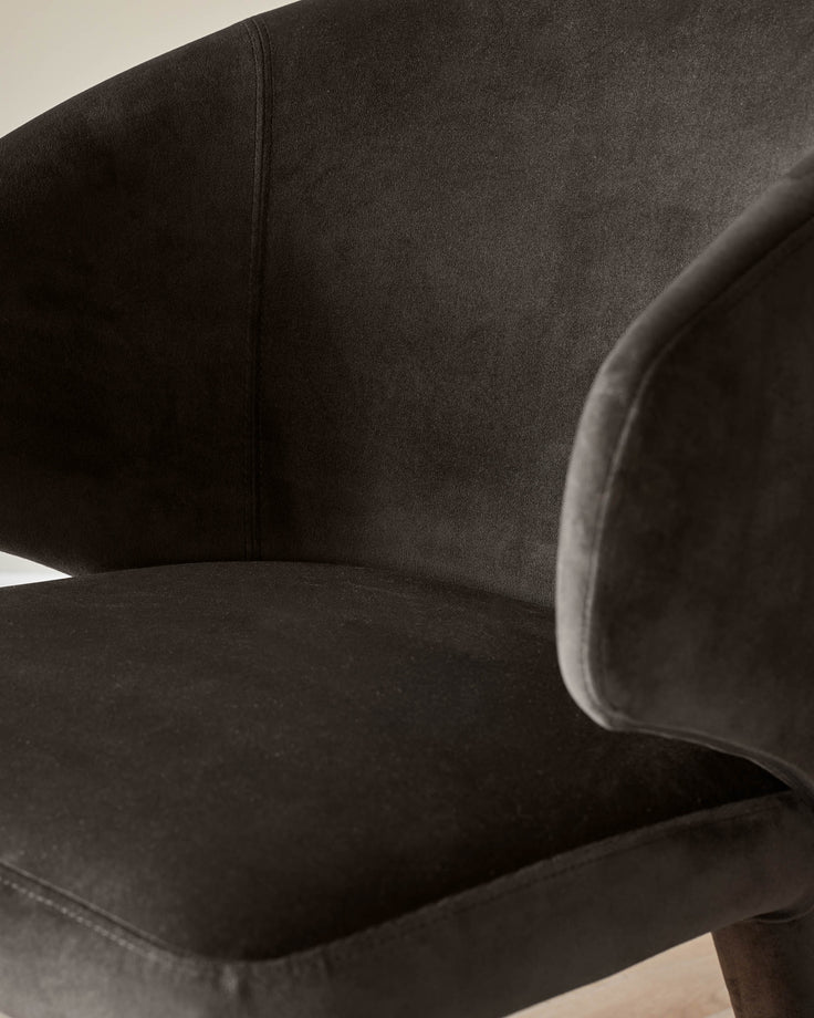 Close-up of a stylish, brown velvet chair showing the seat and armrest. Modern design for comfortable living.