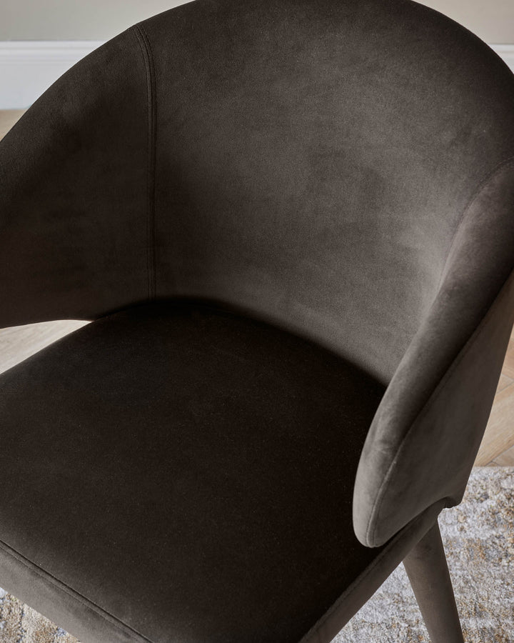 Close-up of a stylish, brown velvet armchair, showcasing its curved design and plush upholstery.