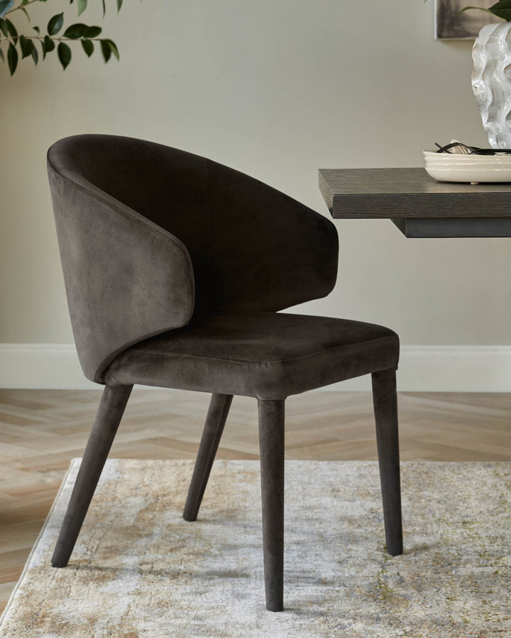 A stylish brown upholstered dining chair with a curved back, sat on a patterned rug next to a wooden table.