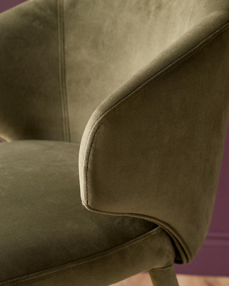 Ethan bar stool in olive green velvet, close-up detail of curved armrest and stitching.