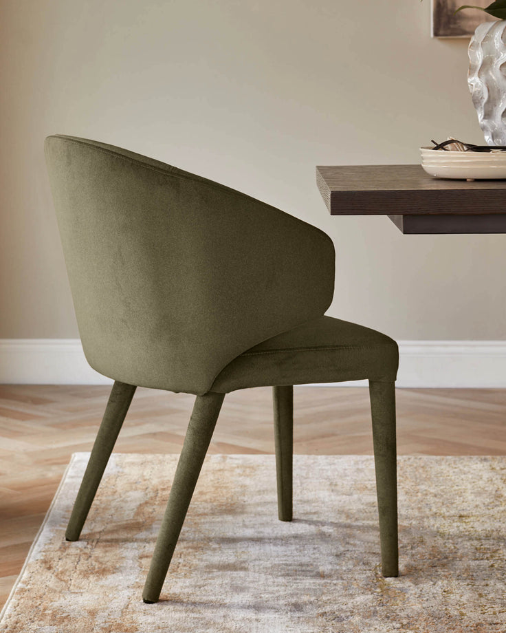 Olive-green upholstered chair with arms and straight, slender legs, next to a wooden table on a neutral rug.
